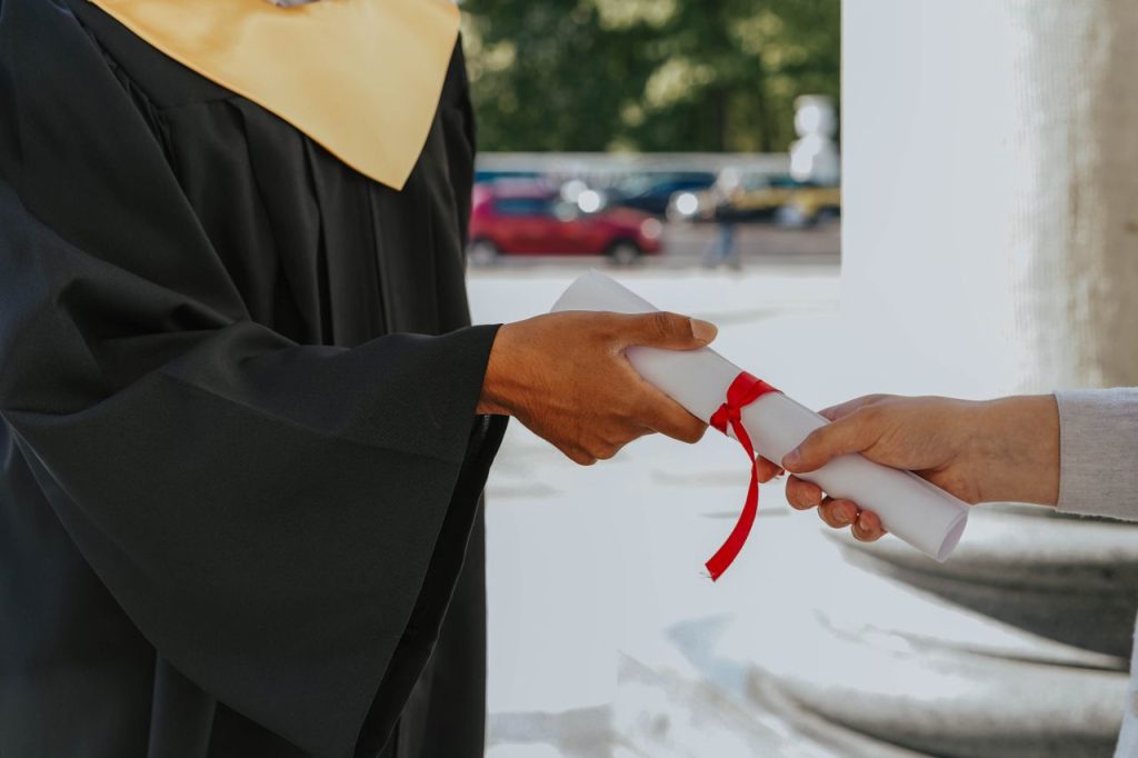 Mastering the First Impression: Your intriguing post title goes here Close-up of a graduate receiving a diploma outdoors in cap and gown.
